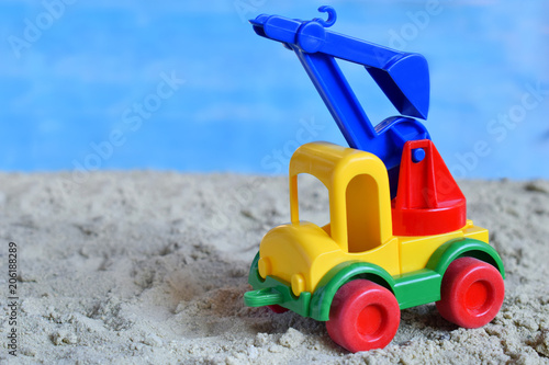 Conceptual photo picture of plastic car in desert. Children's toy. Children play in the sand. The concept of a happy childhood. Kids toys excavator