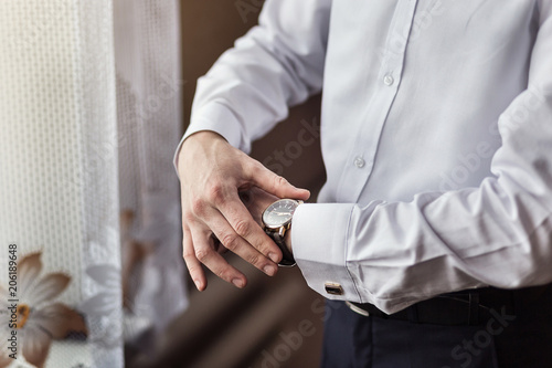 businessman checking time on his wrist watch, man putting clock on hand,groom getting ready in the morning before wedding ceremony