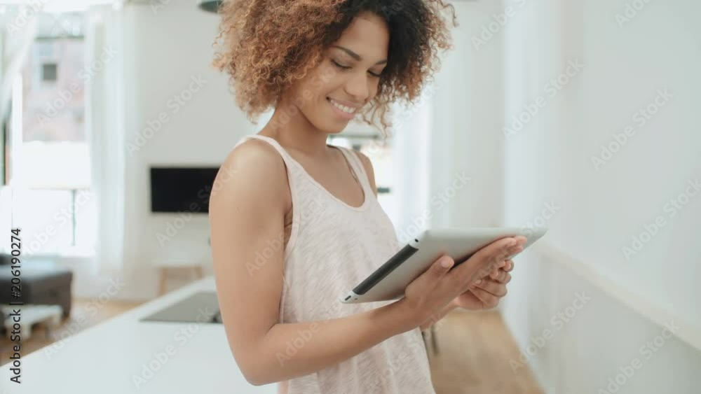 Smiling happy afro american woman using pc tablet at home. Smiling happy afro american woman using pc tablet at home.