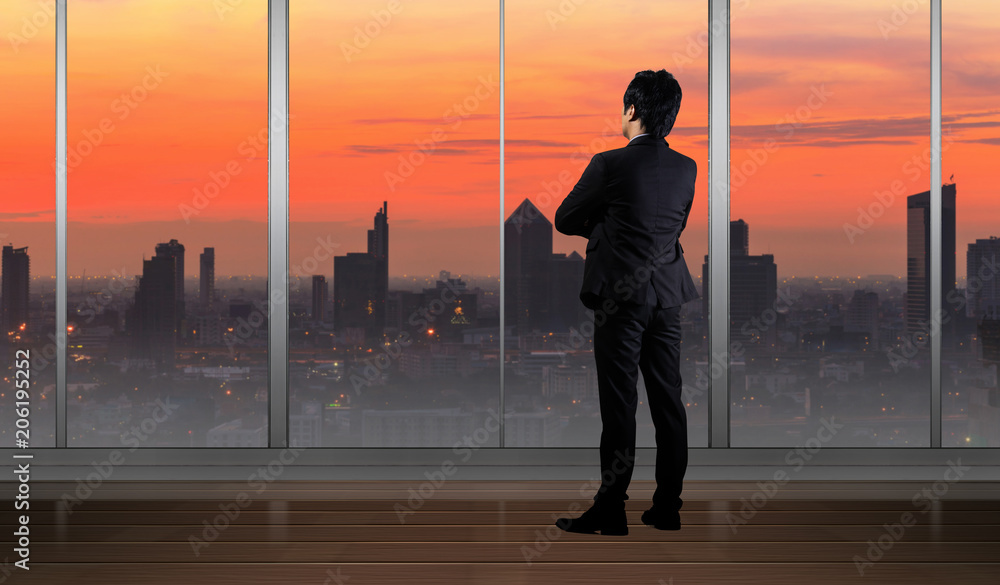 Businessman standing in Office building looking at Cityscape skyline night light Businessman standing in Office building looking at Cityscape skyline night light