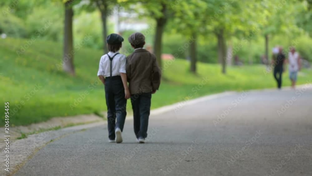 Little preschool boys, cute children, brothers, dressed in vintage style clothes, in a park under blooming trees, looking fashionable, walking away on a path Little preschool boys, cute children, brothers, dressed in vintage style clothes, in a park under blooming trees, looking fashionable, walking away on a path