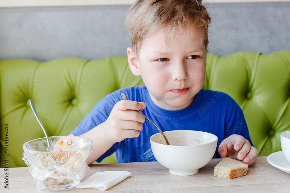 little boy is appetizing eating a delicious soup with a big spoon