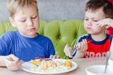 two boys eating pasta with a cutlet