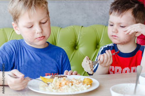 two boys eating pasta with a cutlet