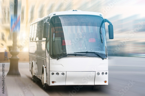 Modern transport bus on asphalt rides at high speed, front view.