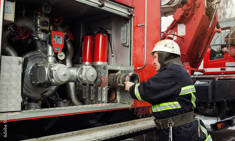 Fototapeta premium Fireman (firefighter) in action standing near a firetruck. Emergency safety. Protection, rescue from danger.