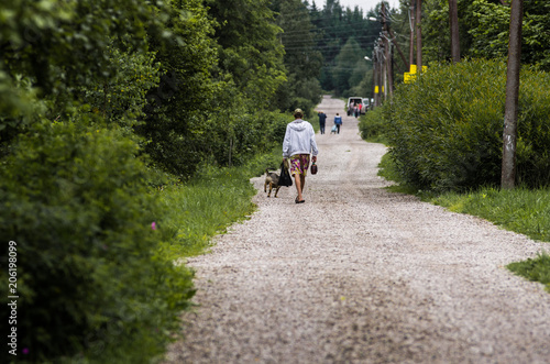 A man with a dog walks on a road in the countryside © Michael Kachalov