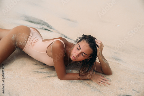 Charming girl in a bikini on summer vacation. A delightful woman with curly hair bathes in the ocean on a desert island in a swimsuit. Wet sexy tanned model body.