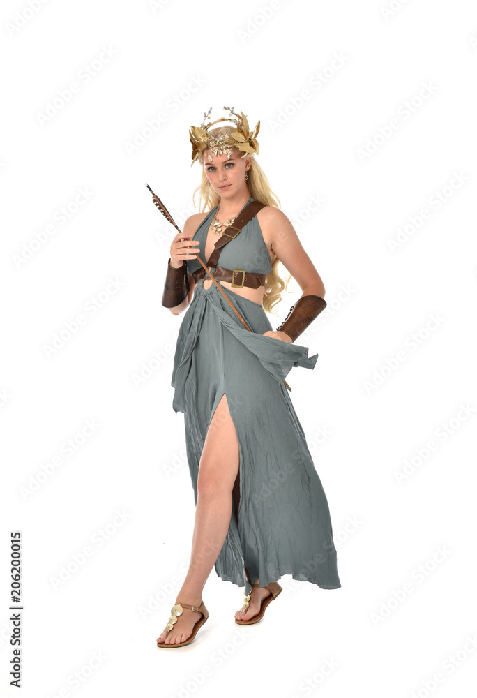 full length portrait of pretty blonde lady wearing fantasy toga gown, and holding a bow and arrow. standing pose on white background. full length portrait of pretty blonde lady wearing fantasy toga gown, and holding a bow and arrow. standing pose on white background.