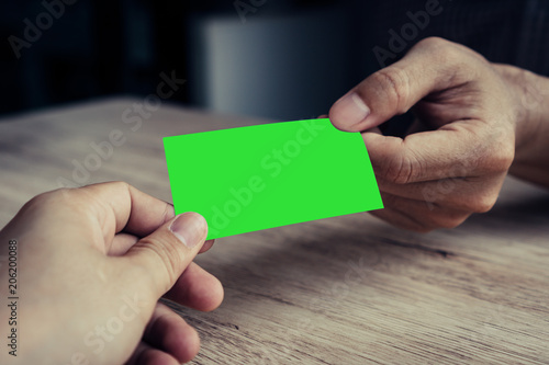 Two businessmen exchanged business cards on a wooden table. Green screen business cards. Copy space. Vintage Style. Business Concepts.
