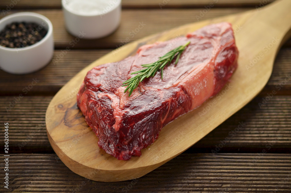 Raw beef fillet steaks with herbs and spices on wooden background