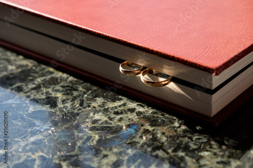 Brown leather covered wedding album with pair of wedding golden rings  end face.