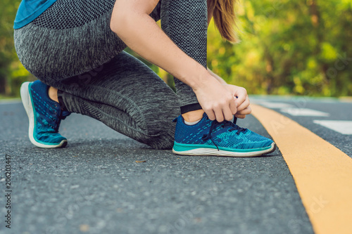 Female runner tying her shoes preparing for jogging outside .Young girld runner getting ready for training. Sport lifestyle photo