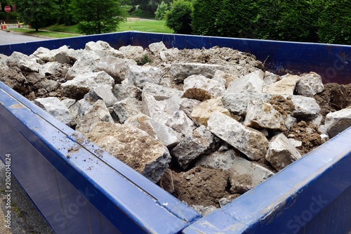 Photos Dumpster filled with sidewalk concrete debris in neighborhood setting