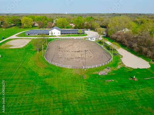 A person mowes the grass at a horse farm and equestrian center on  a summer day