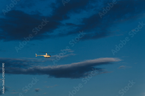 Horizontal view of small helicopter in blue sky flies very high. Small plane for signtseeing. Outdoor shot. Transport concept. Chopper in air photo