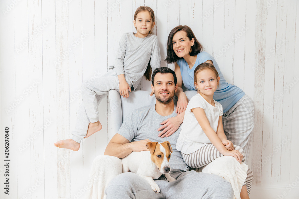 Friendly family of four memebers: cheerful European brunette female, her husband, two daughters and favourite pet, have good relationships, support each other. Affectionate parents with children Friendly family of four memebers: cheerful European brunette female, her husband, two daughters and favourite pet, have good relationships, support each other. Affectionate parents with children