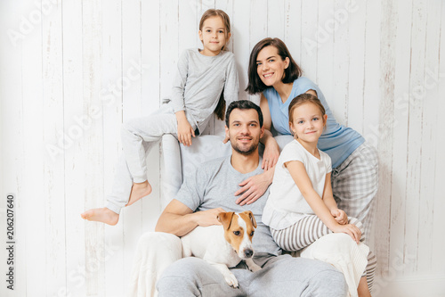 Friendly family of four memebers: cheerful European brunette female, her husband, two daughters and favourite pet, have good relationships, support each other. Affectionate parents with children photo