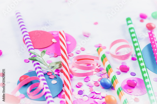Cocktail straws, confetti and candies close-up in a colorful party supplies concept on a light background with copy space. Holiday accessories