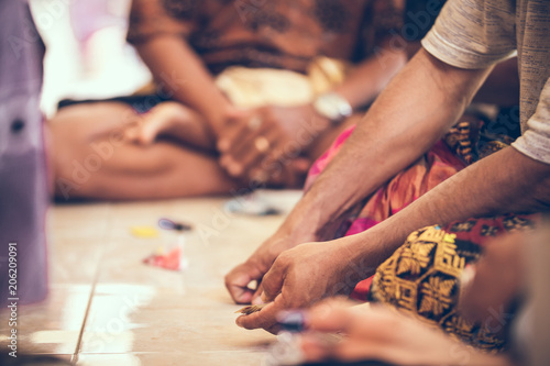 Group of balinese men playing cards sitting on the floor. Bali island.