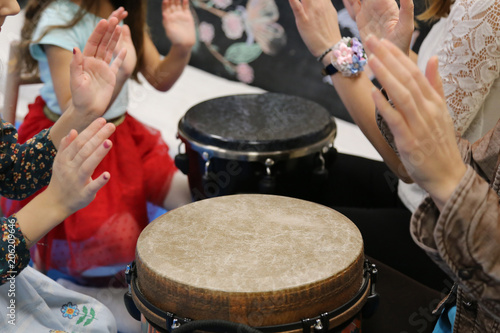 Kids play jembe drum in a montessori music therapy classroom with parents, hands close up photo