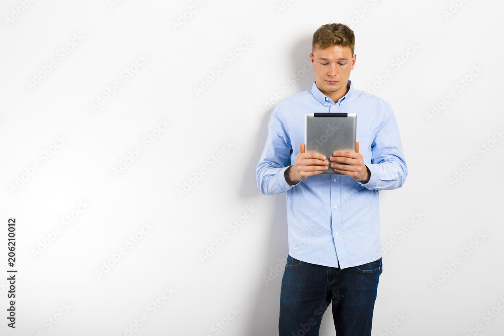 Young man looking up and standing against white wall. Young man looking up and standing against white wall.