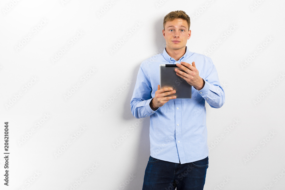 Young man looking up and standing against white wall. Young man looking up and standing against white wall.