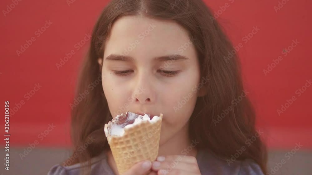 Pretty baby girl kid eating slow motion video nursing bottle licking big ice cream lifestyle in waffle cone with raspberry happy laughing on red background. the girl teenager and ice cream concept Pretty baby girl kid eating slow motion video nursing bottle licking big ice cream lifestyle in waffle cone with raspberry happy laughing on red background. the girl teenager and ice cream concept