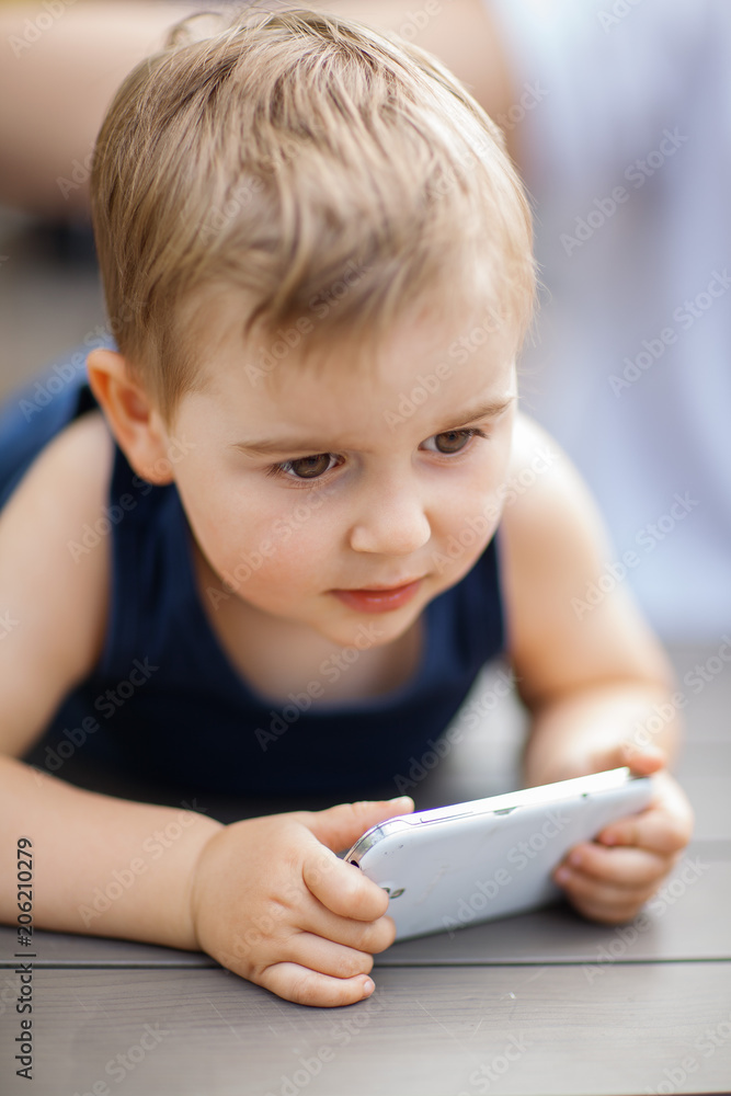 little boy sits next to dad and is highly concentrated with a cell phone in his hands little boy sits next to dad and is highly concentrated with a cell phone in his hands