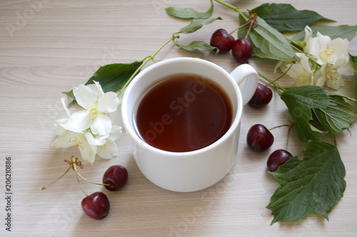 Cup of tea, cherry and flowers on the table