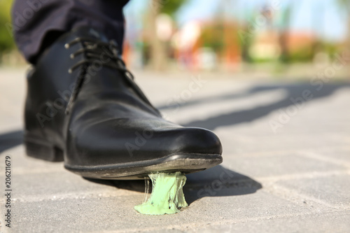 Fotografie Man stepping in chewing gum on sidewalk. Concept of stickiness