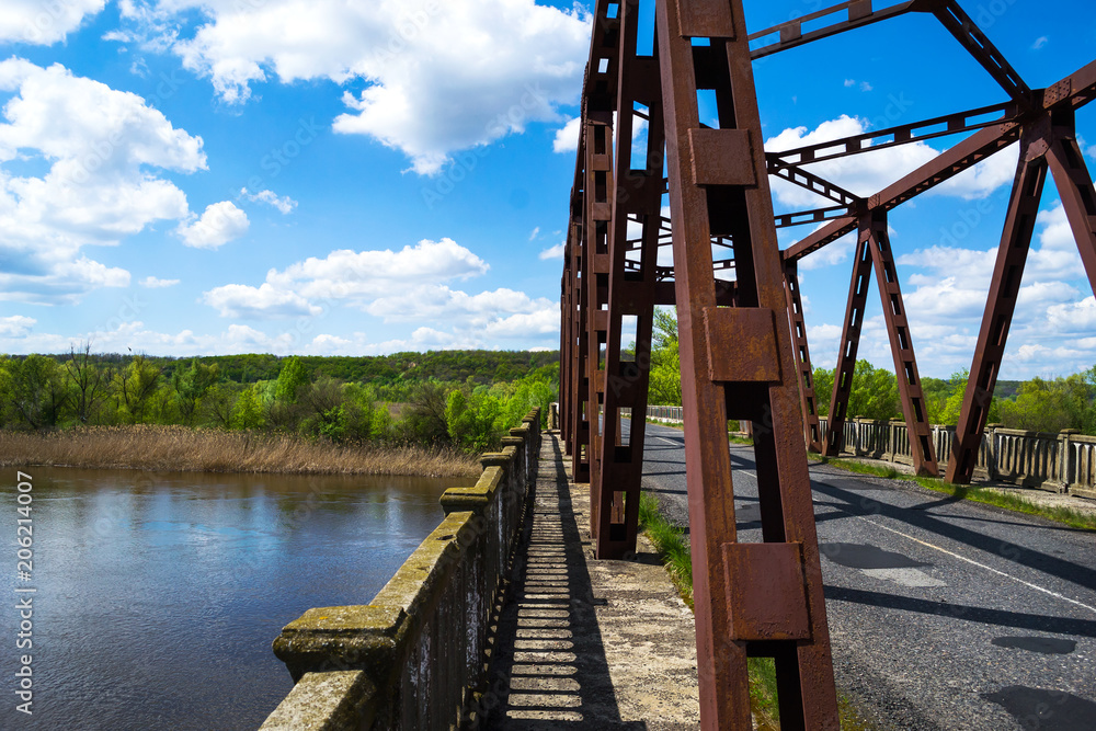 Old car bridge over the river. The blue cloudy sky. Sunny summer day. Travel