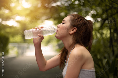 Asian woman drinking water from a bottle.