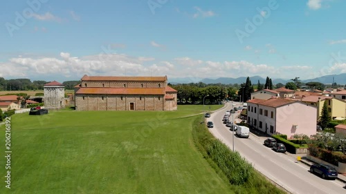 Aerial view of medieval cathedral surrounded by meadows in Tuscany