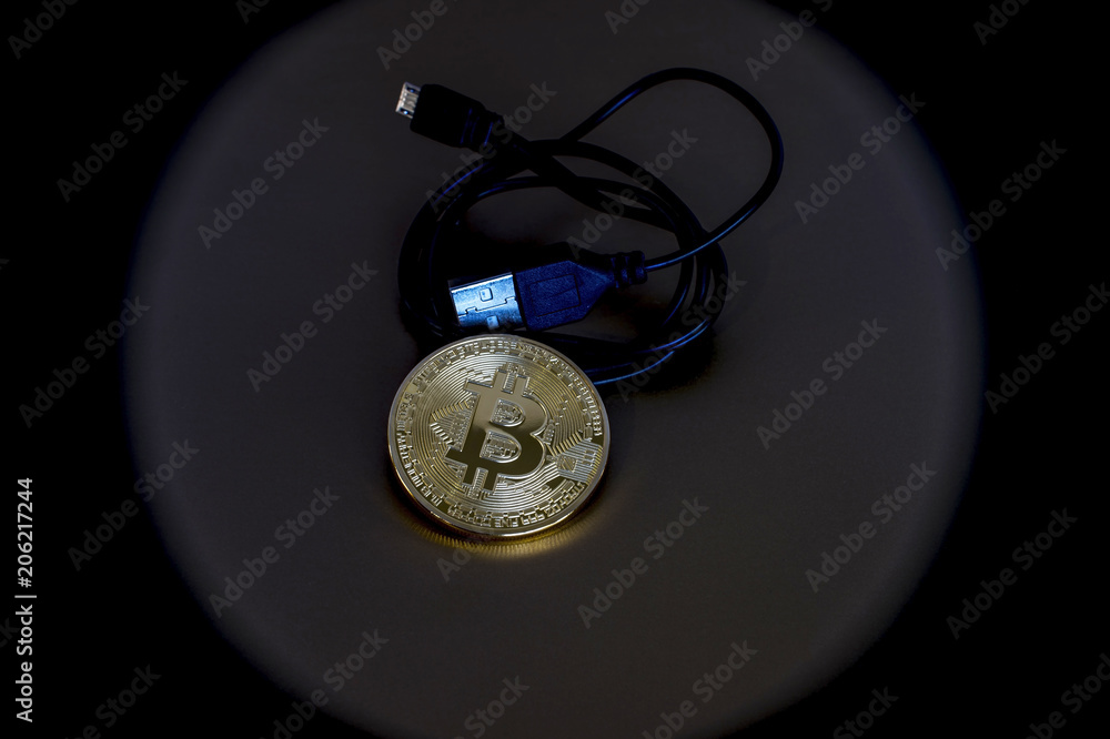 Digital kriptonite bitcoin with a USB cable on a bronze background. Digital kriptonite bitcoin with a USB cable on a bronze background.