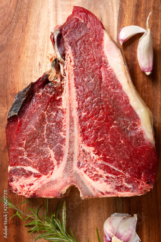Meat for a barbecue. One raw piece of beef meat on the bone. steak t bone, salt, spices on a wooden kitchen board top view. The best piece of meat eight weeks maturation