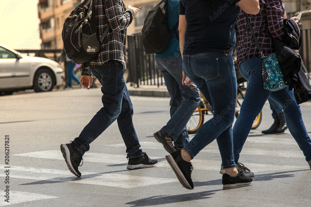 People stranded and distracted crossing the street in the pedestrian crossing at a busy intersection crowded and crowded in the midst of traffic only showing up the legs and feet. Walking and talking People stranded and distracted crossing the street in the pedestrian crossing at a busy intersection crowded and crowded in the midst of traffic only showing up the legs and feet. Walking and talking