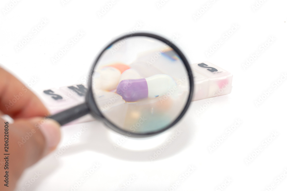 Fototapeta premium magnifying glass with colorful pill in the box