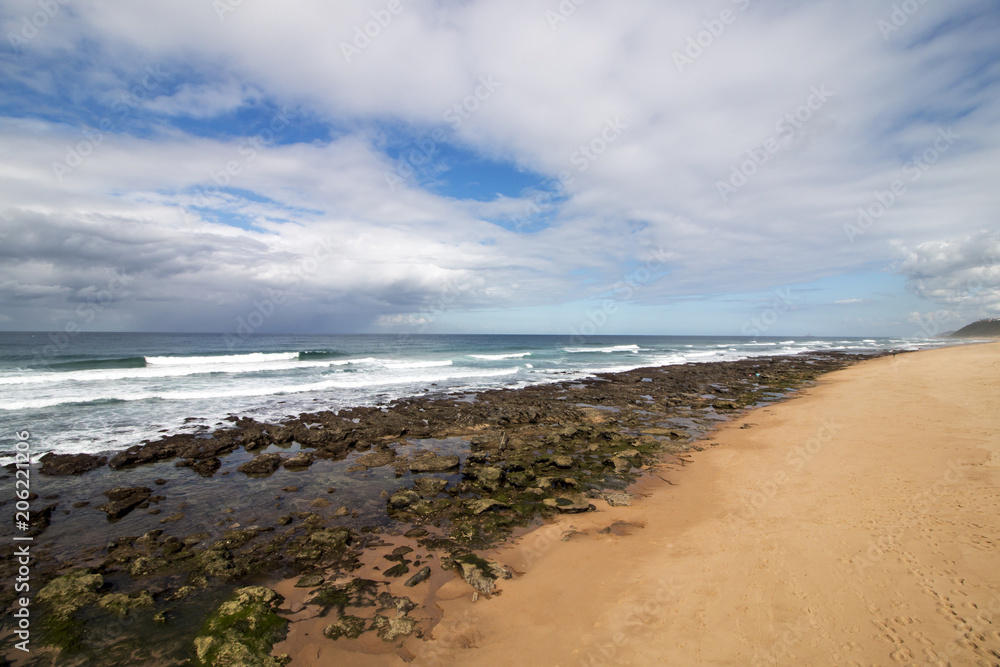 Rocky Beach Waves and Ocean Against Blue Cloudy Skyline Rocky Beach Waves and Ocean Against Blue Cloudy Skyline