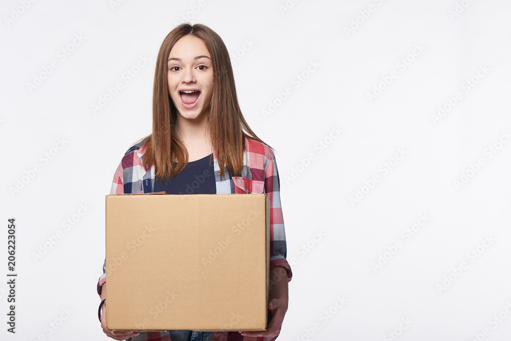 Happy excited woman holding cardboard box with expression of surprise, over white background Happy excited woman holding cardboard box with expression of surprise, over white background