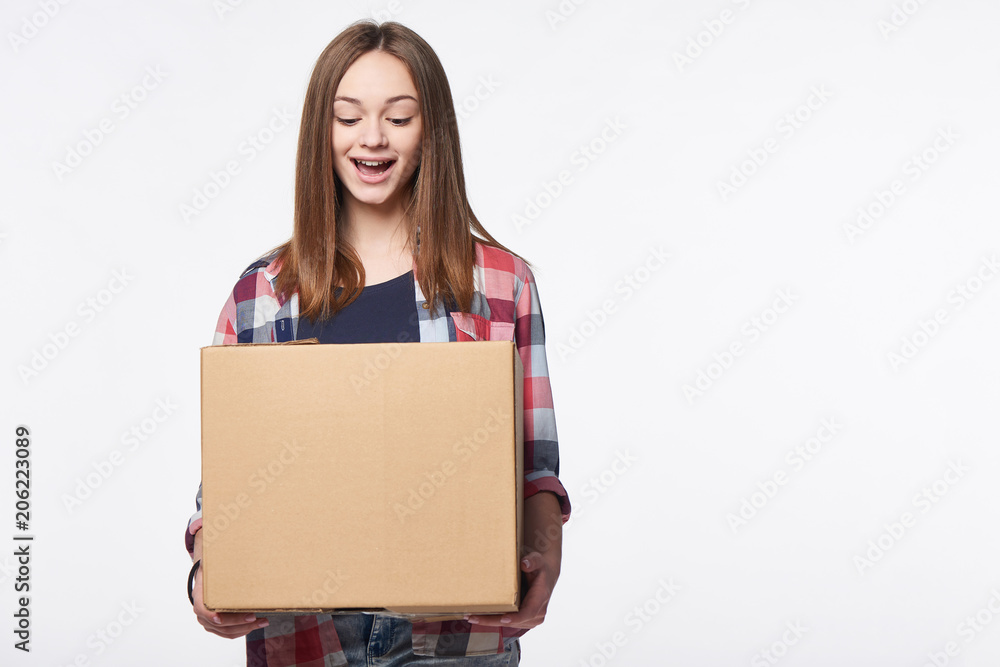 Happy excited woman holding cardboard box with expression of surprise, over white background Happy excited woman holding cardboard box with expression of surprise, over white background