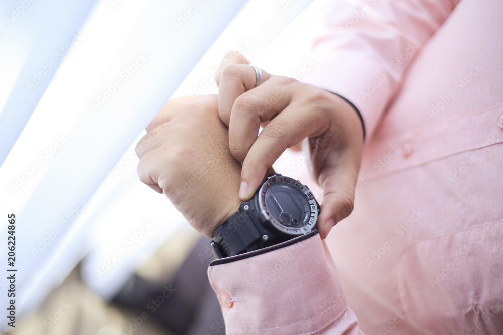 The groom wears and adjust a wristwatch. The groom looks at his watch. Wedding detail preparation. The groom wears and adjust a wristwatch. The groom looks at his watch. Wedding detail preparation.