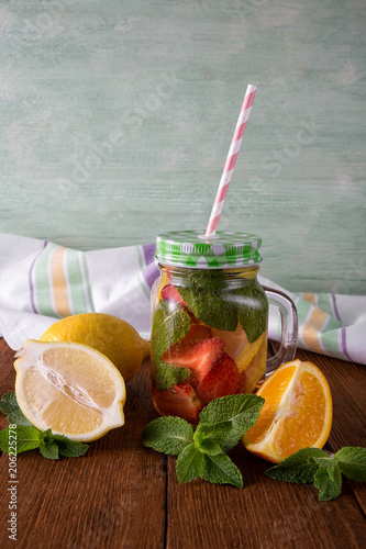 Fruit fresh lemonade in mugs on wooden background with napkin and mint