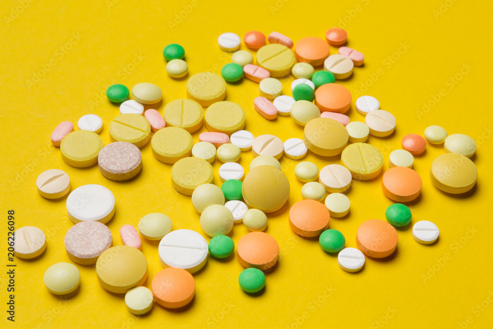 on the yellow surface scattered multicolored pills, the concept of medicine and allergy
