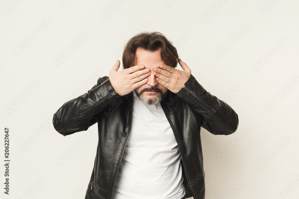 Middle-aged man covering eyes with hands, see no evil Middle-aged man covering eyes with hands, see no evil