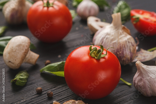 Fresh tomatoes and garlic closeup on dark rustic wood