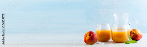 Fotografie peach juice in glasses and a decanter and fresh peaches with lea