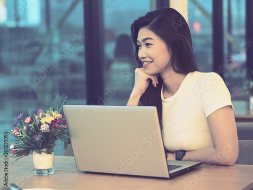 Happy Beautiful Asian young woman working with laptop and smile and looking outside office with positive emotional,Business Startup Concept