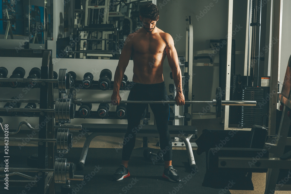 Strong and handsome young man doing exercise with dumbbells Strong and handsome young man doing exercise with dumbbells