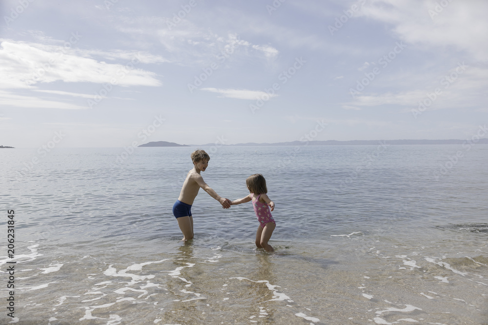 Brother and little sister playing together at seafront Brother and little sister playing together at seafront
